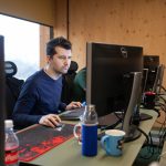 modern developer at desk with AI coding assistant floating above screen