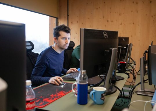 modern developer at desk with AI coding assistant floating above screen